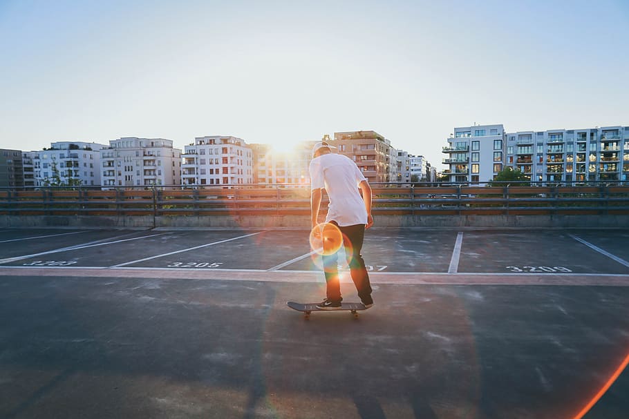 man wearing white t-shirt and black pants standing on skateboard during daytime, HD wallpaper