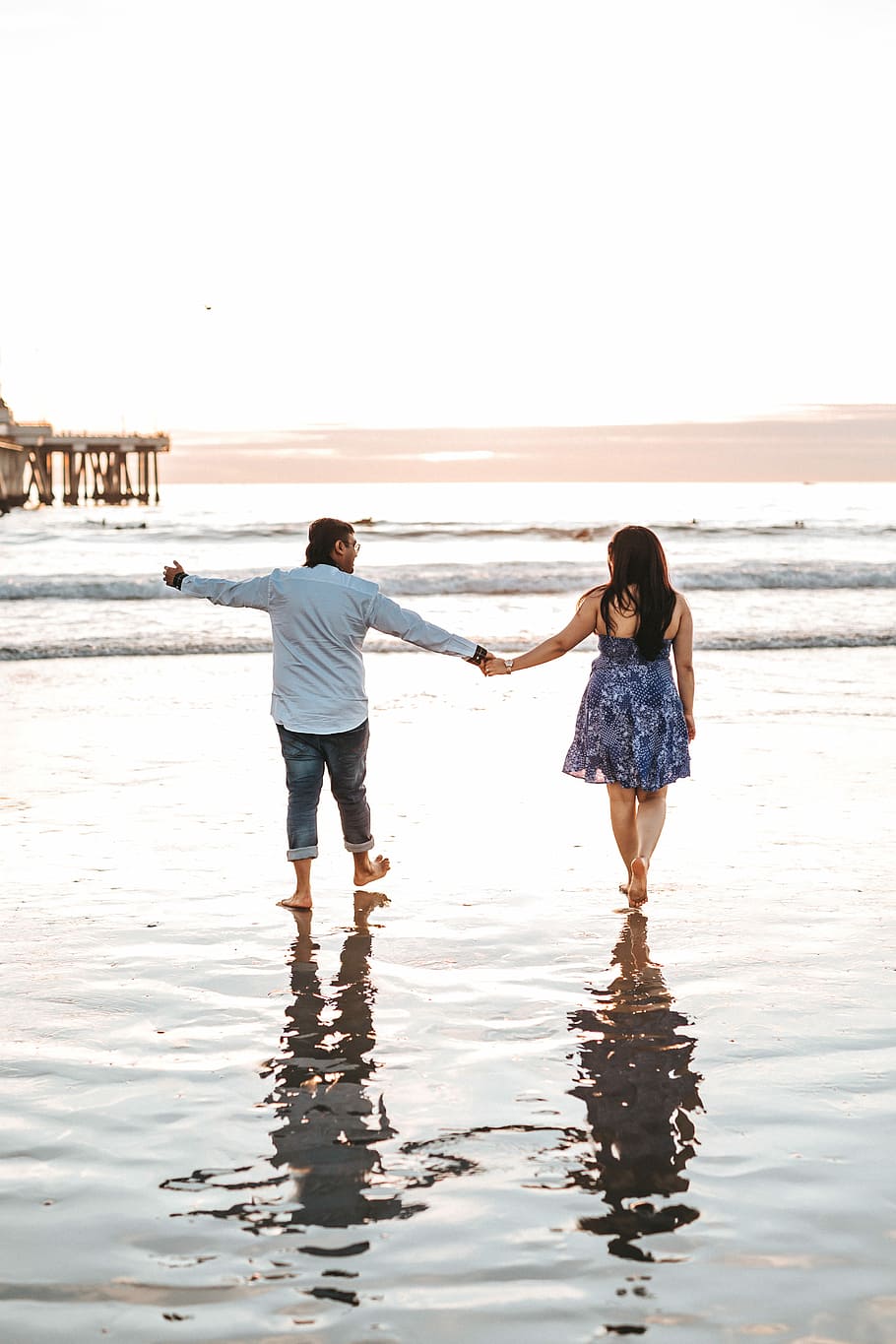 man and woman holding hands while walking on seashore, couple walking at shoreline HD wallpaper