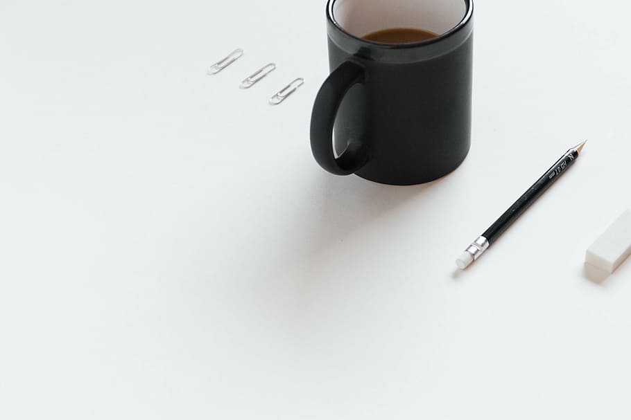 black coffee mug beside pencil, near, white, eraser, surface