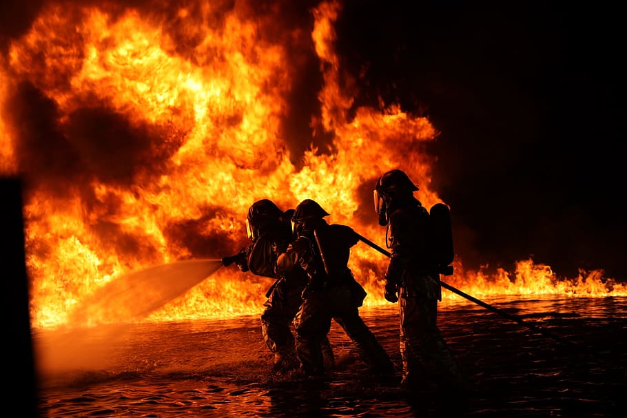 silhouette of three firefighters surrounded by fire, portrait