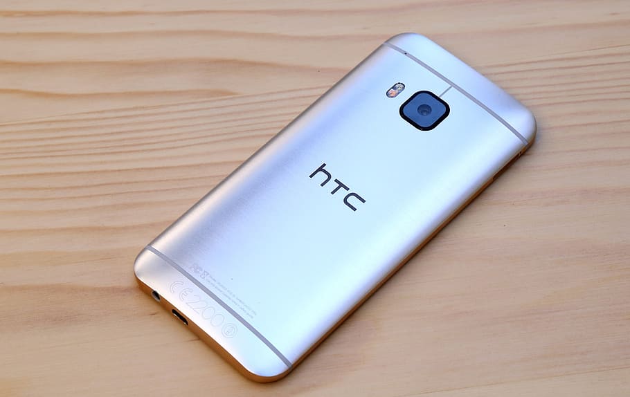 silver HTC Desire One M9 on brown surface, htc one, htc one m8