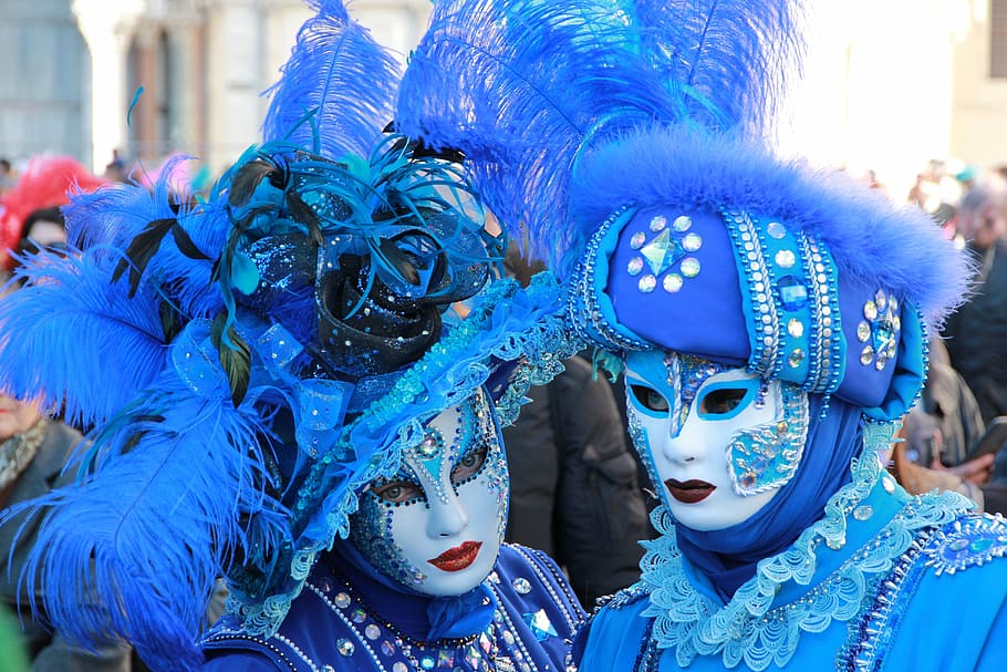 person gathered on street wearing masquerade masks, suit, colors