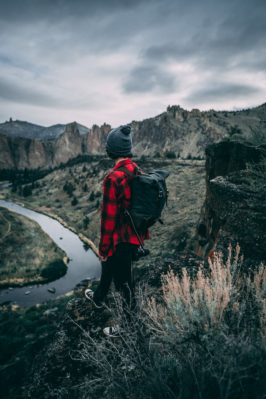 person standing on the cliff, man in red and black plaid dress shirt on top of mountain during daytime HD wallpaper