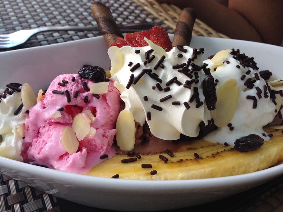 sliced banana top with strawberry and vanilla ice cream drizzled with nuts and chocolate sprinkles