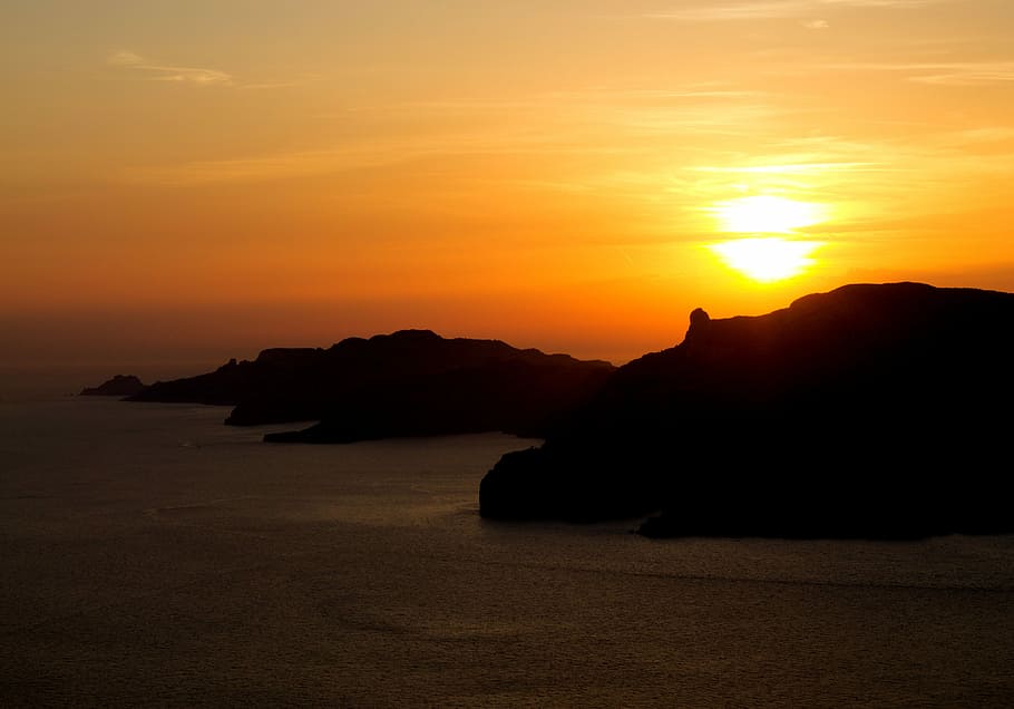 aerial photo of island during sunset, black mountain on body of water HD wallpaper