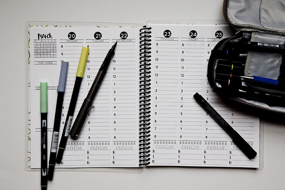 open notebook with five assorted pens on white white surface HD wallpaper