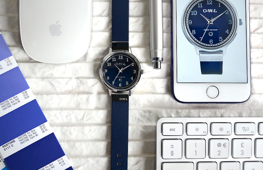 round blue analog watch surrounded by iPhone, Apple Magic Mouse, and pen HD wallpaper