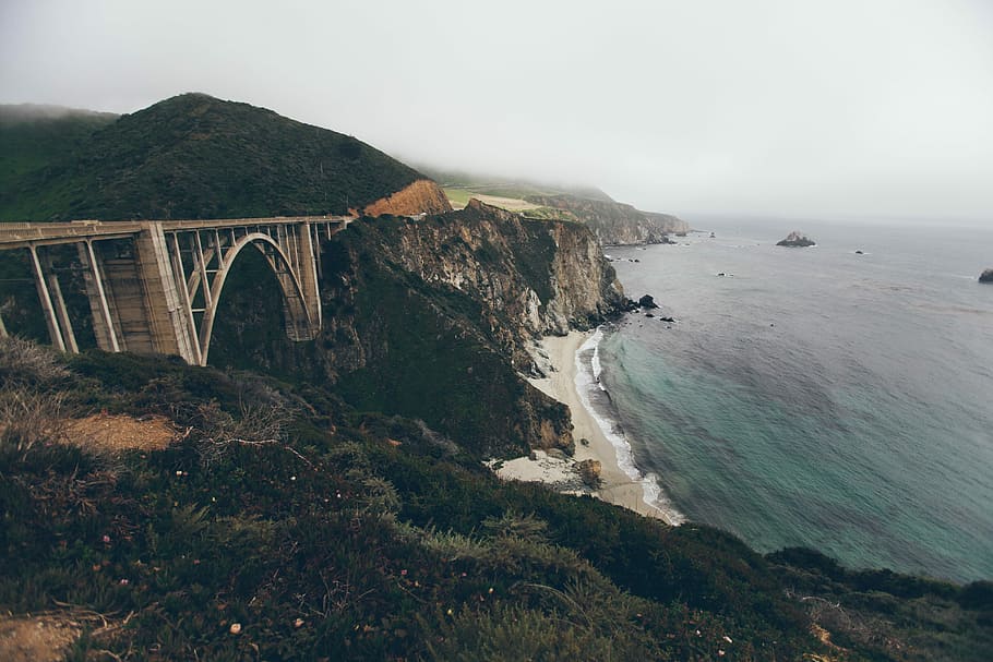 landscape photography of green cliff, bridge between mountains near body of water HD wallpaper