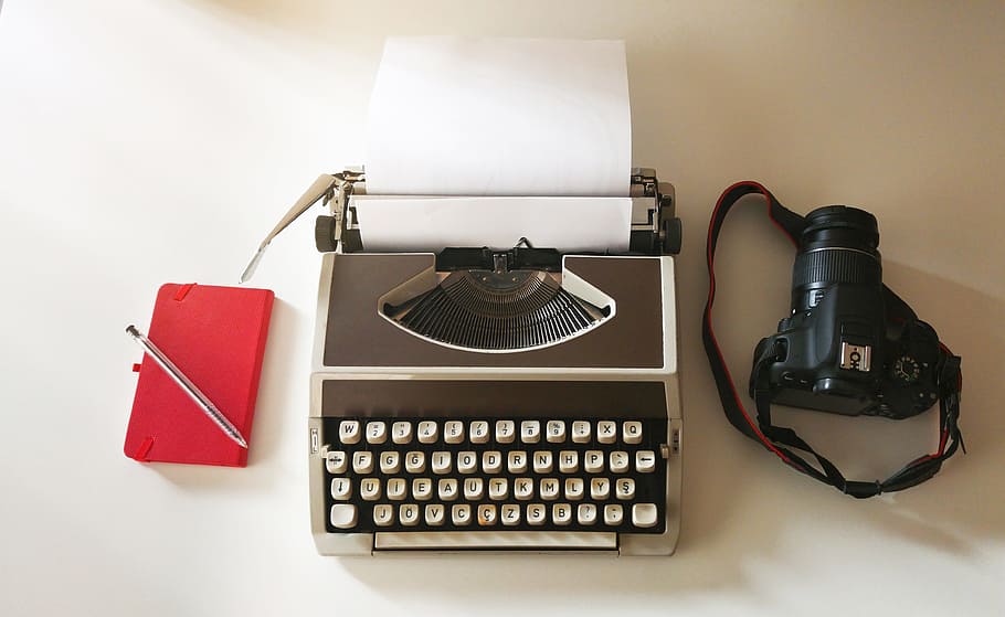 black DSLR camera; grey typewriter; red tablet computer flip case HD wallpaper
