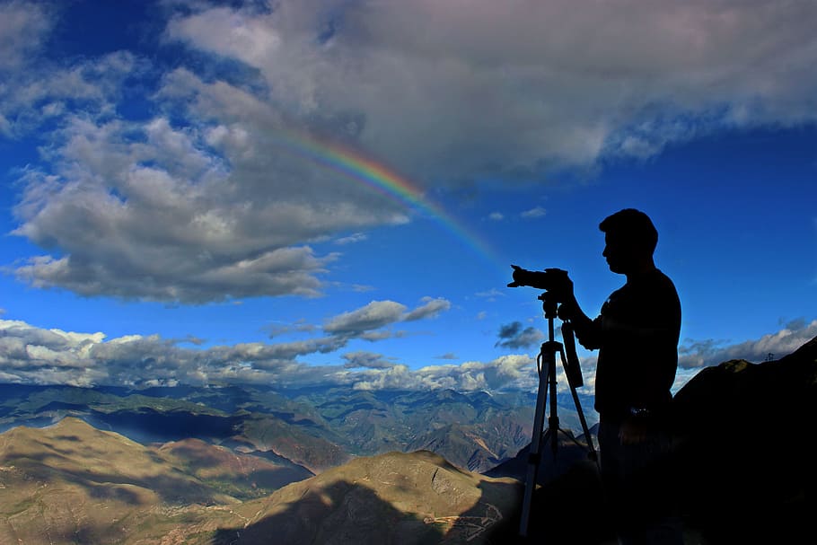 silhouette photo of holding camera with stand during daytime with rainbow, grayscale photography of man holding camera with tripod HD wallpaper