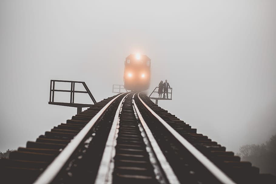 man and woman standing beside trailway, photograph of two people standing on waiting area beside transit track HD wallpaper