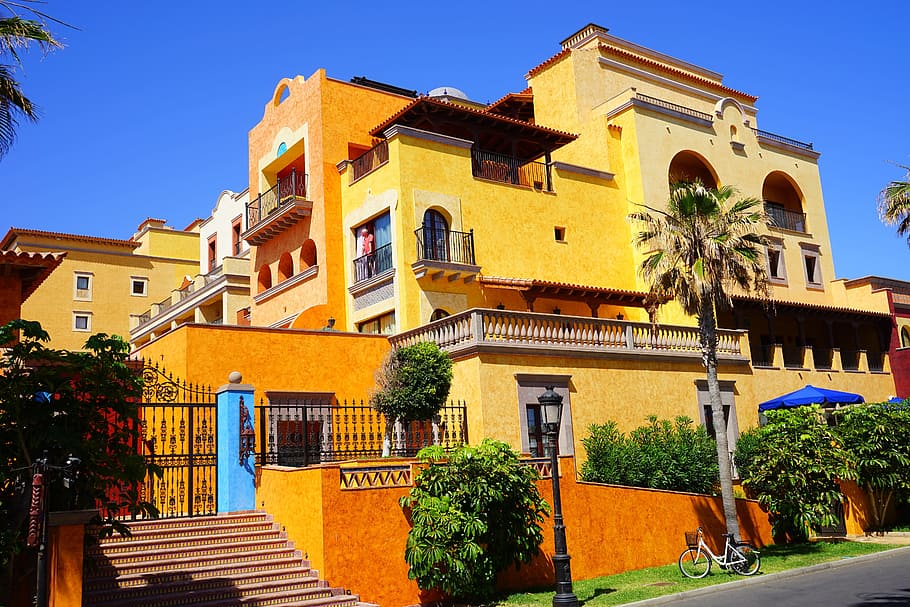 orange and beige concrete multi-storey building near palm trees HD wallpaper