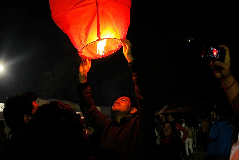 man in b lack jacket holding sky lantern, night, people, crowd HD wallpaper