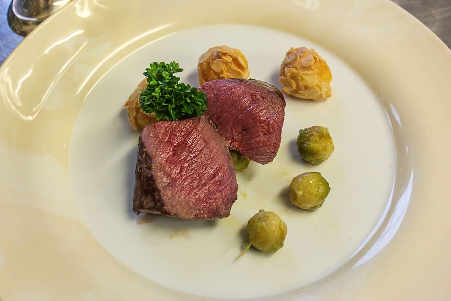 grilled meat on white ceramic plate, venison, brussels sprouts