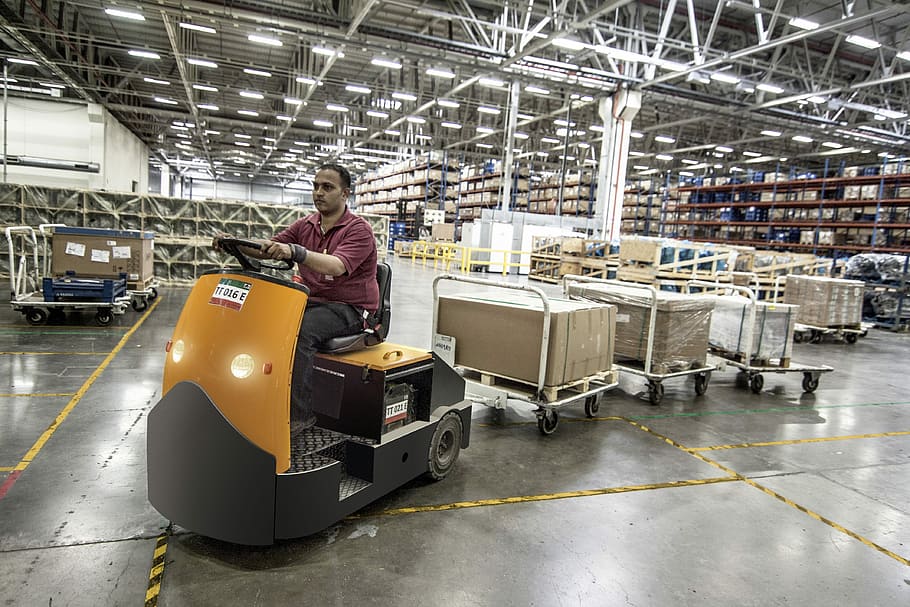 man driving cart with boxes inside building, forklift, warehouse