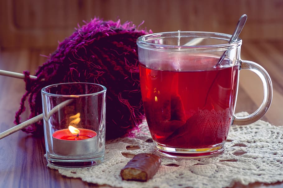 clear glass mug filled with tea beside clear glass tealight holder and purple fleece textile HD wallpaper