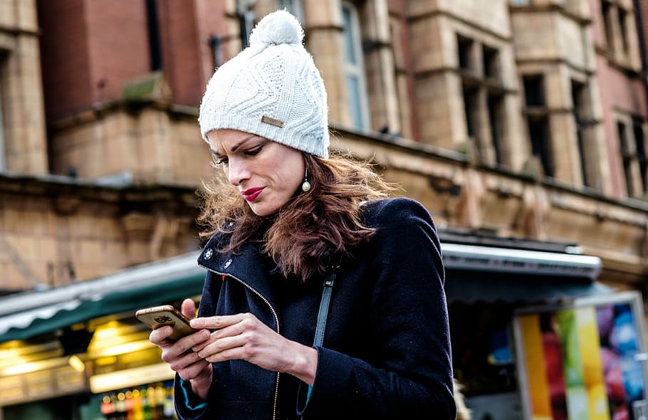 Studious…, woman holding Android smartphone, female, hat, city, HD wallpaper