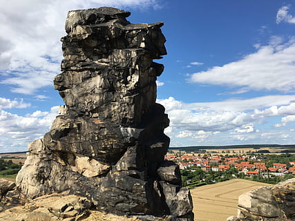photo of gray rock formation on hill across brown roof house lot during daytime HD wallpaper