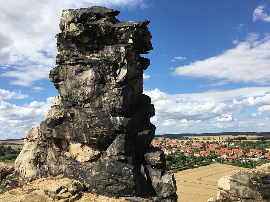 photo of gray rock formation on hill across brown roof house lot during daytime HD wallpaper