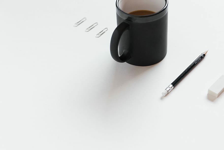 three gray paper clip beside black ceramic coffee mug and pencil on white surface close-up photo HD wallpaper