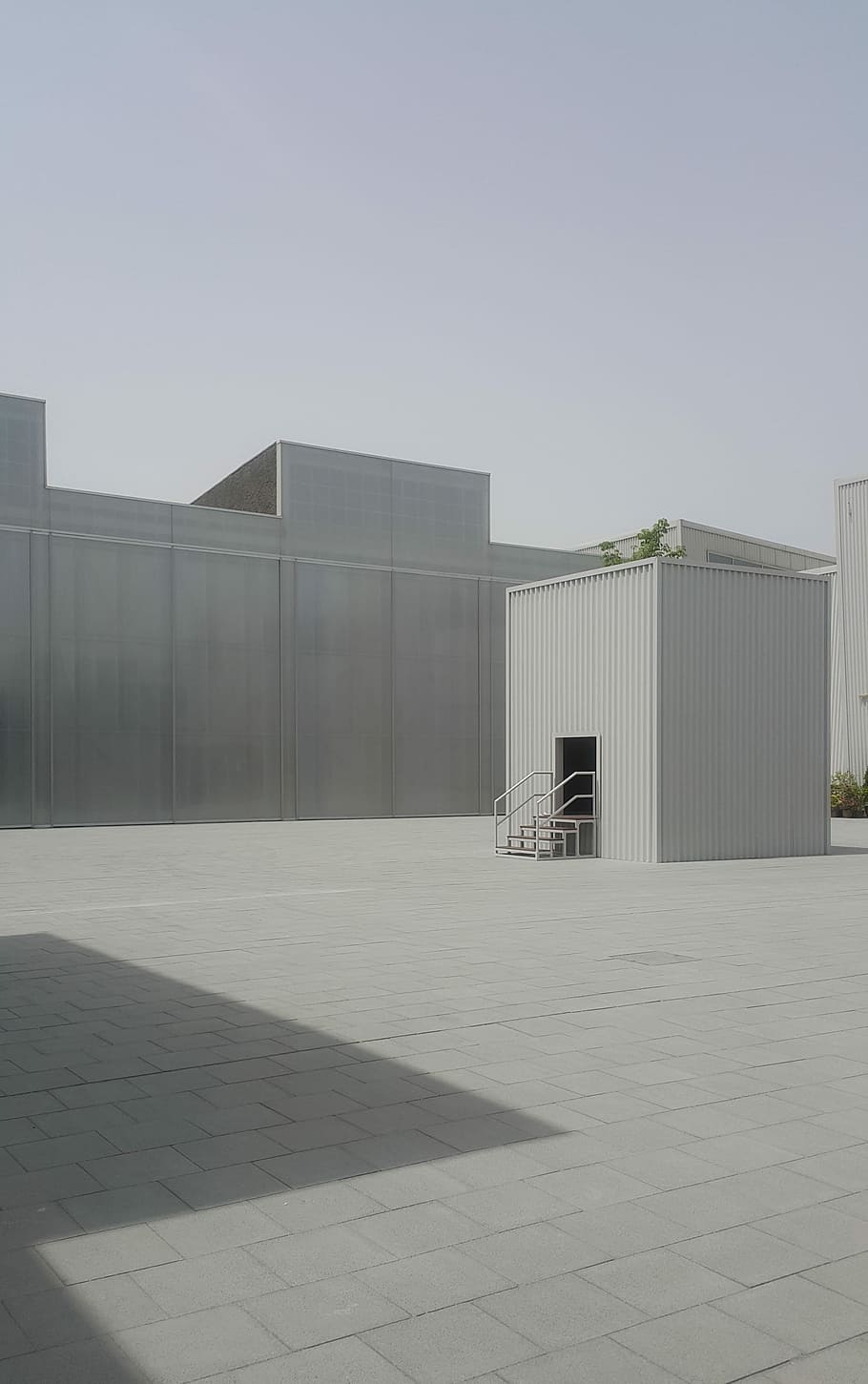 white metal shed near building, square white metal shed surrounded by white buildings at daytime HD wallpaper