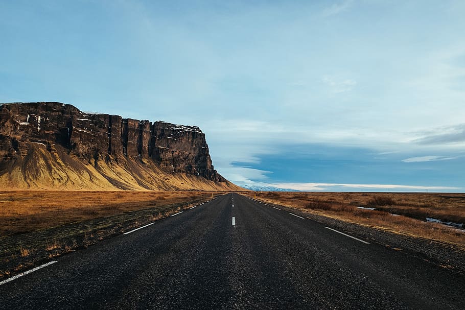 gray asphalt road in the middle of desert near black mountain during daytime, rocky mountain near asphalt road during daytime HD wallpaper