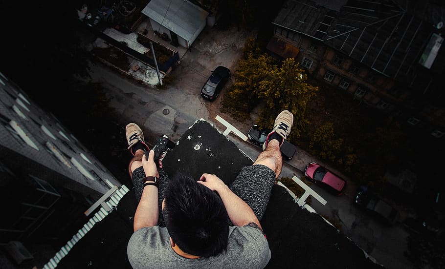 man sitting on ledge, looking down, person, rooftop, sat, high angle view