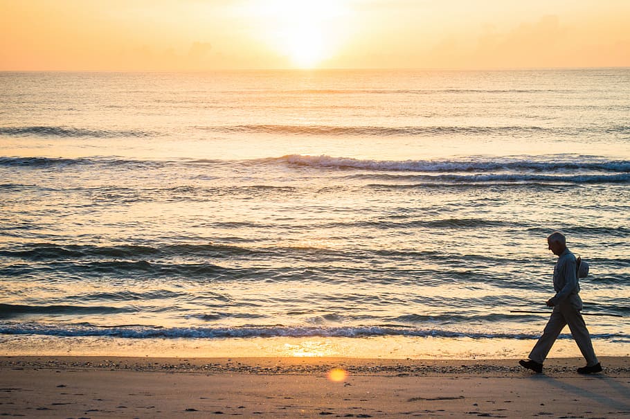 man walking beside ocean at sunset, man walking on seashore during sunset HD wallpaper