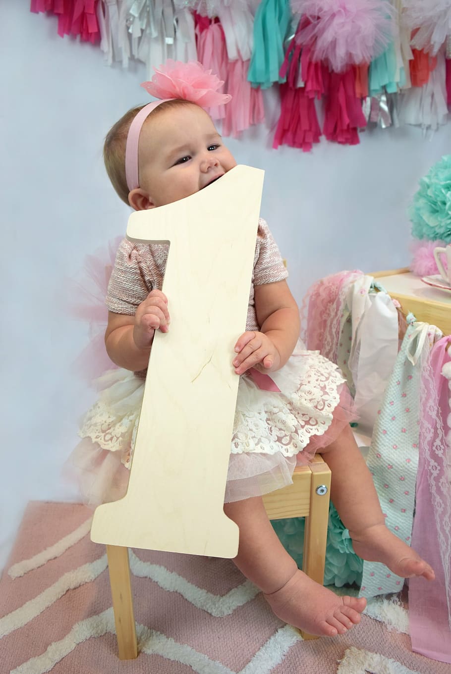 girl holding letter 1 standee while sitting on stool, one year old