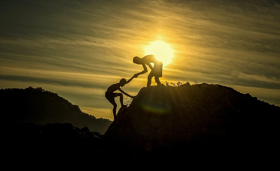 silhouette of man helping another man to climb on cliff during golden hour, HD wallpaper