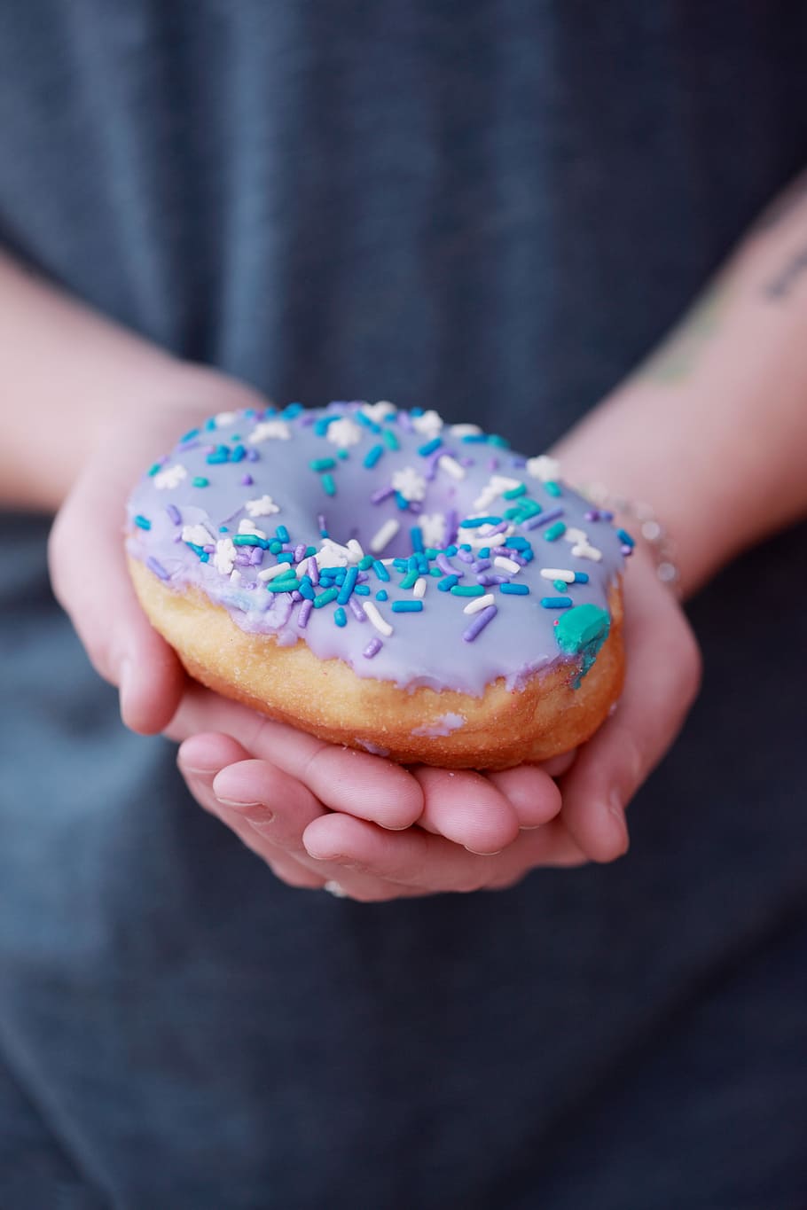 person holding doughnut, person holding a donut with toppinmgs HD wallpaper