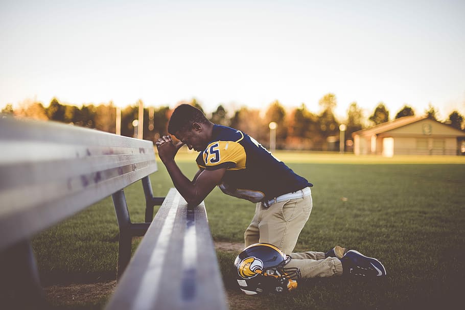 baseball player kneeling on ground, man in yellow and black football jersey shirt kneeling while praying during daytime, HD wallpaper