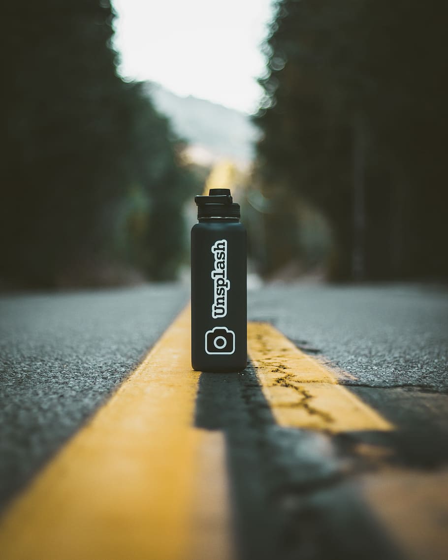 tilt-shift photography of Unsplash bottle, black Unsplash tumbler HD wallpaper