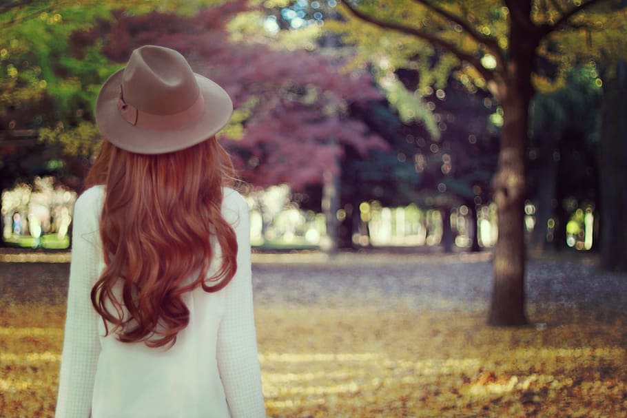 woman wearing hat and white long sleeved dress standing near tall trees at daytime HD wallpaper