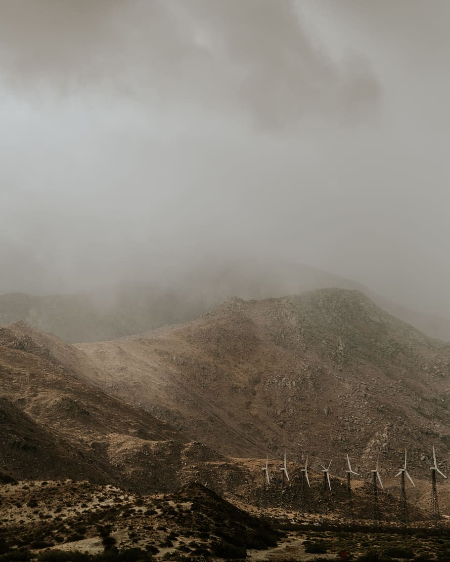 white wind turbines beside mountain, white windmills beside mountain under gray cloudy sky HD wallpaper