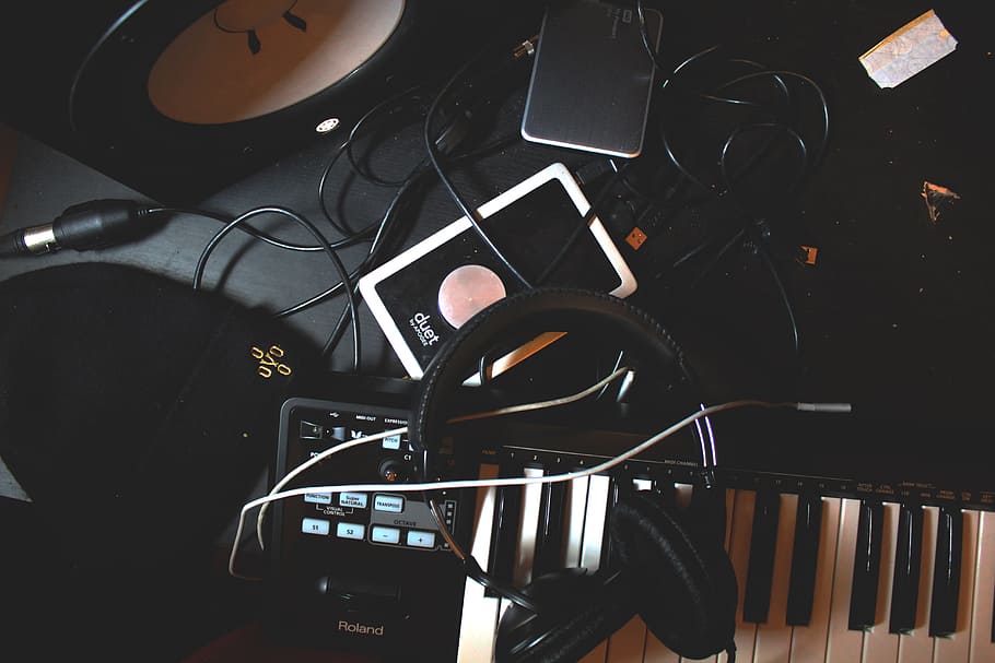 flat-lay photo of headphones, MIDI keyboard, and speaker on black surface, black corded headphones on electronic keyboard