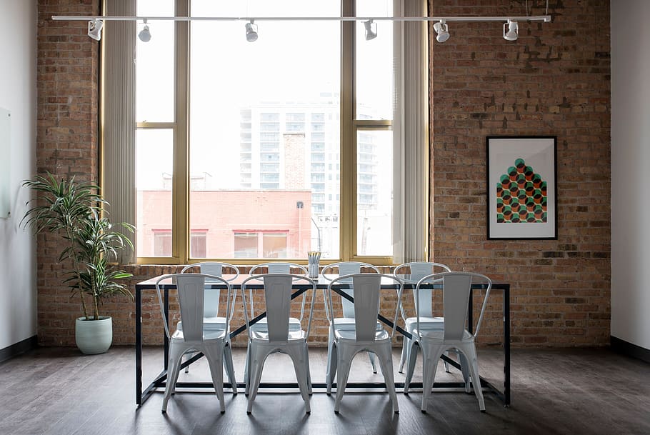 rectangular black metal-framed glass-top table with chairs near window