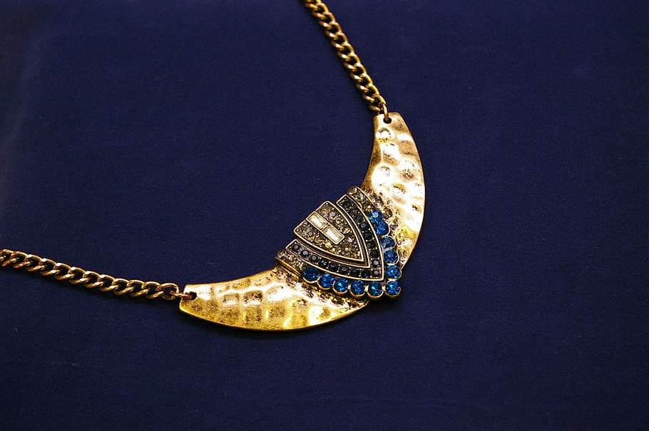 photo of blue gemstone encrusted gold-colored pendant, jewellery