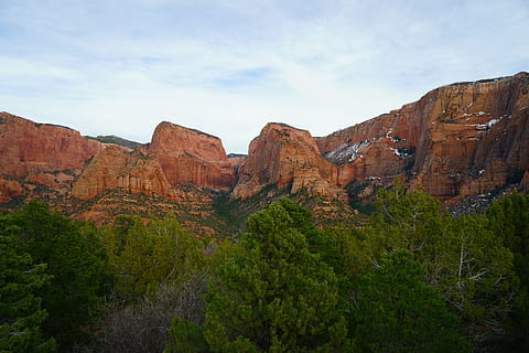 brown mountains near tress at daytime, brown rock formations under blue and white sky HD wallpaper