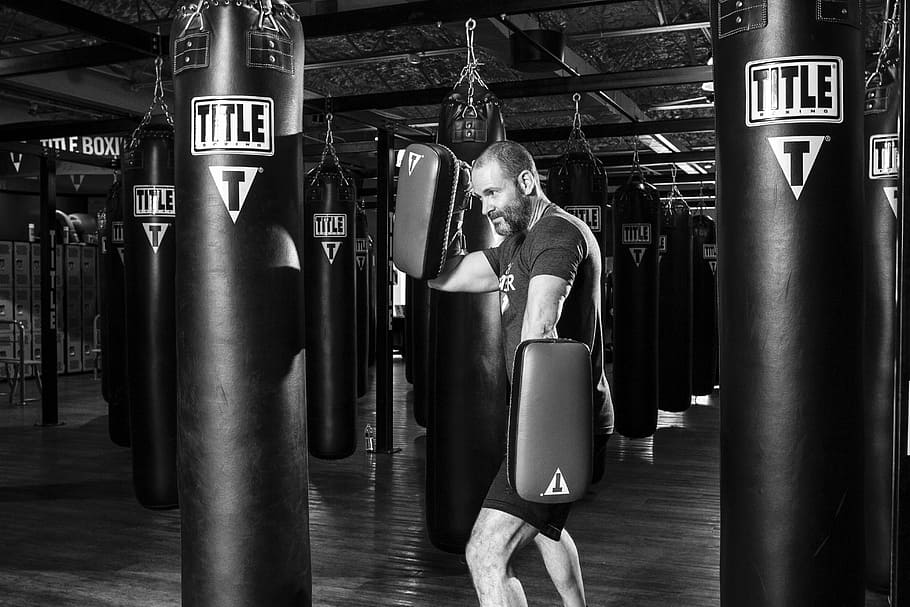 man facing heavy bag holding training gloves, boxer, boxing, sport