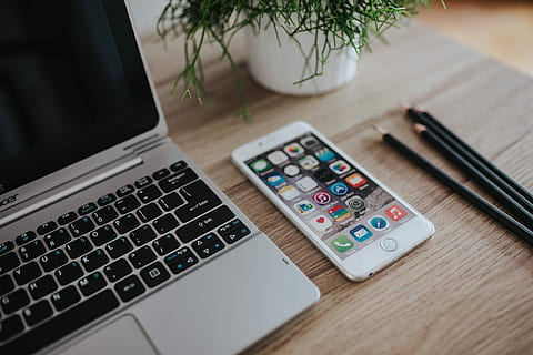 Silver Acer laptop on a wooden desk with a green plant, pencils and an Apple iPhone HD wallpaper