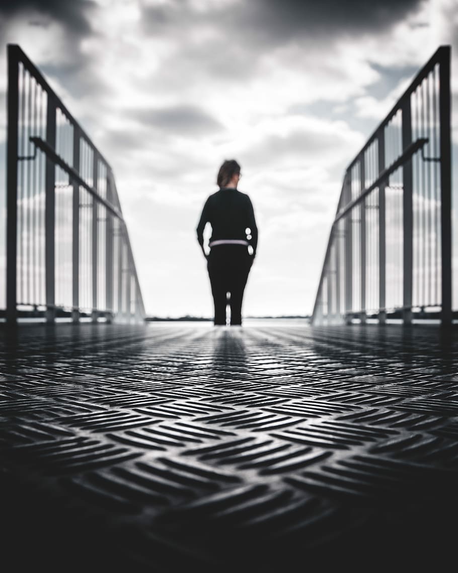 grayscale photo of woman in between gray metal railings, woman in black pants and sweatshirt standing at the end of stairs HD wallpaper