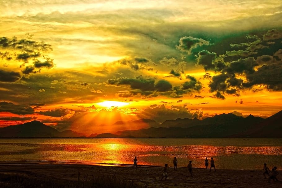 sunset over mountain in sea with people on beach, da nang, vietnam HD wallpaper