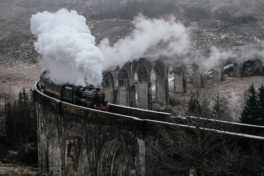 black steam train emitting smoke on concrete railway during daytime, train traveling over river at daytime HD wallpaper
