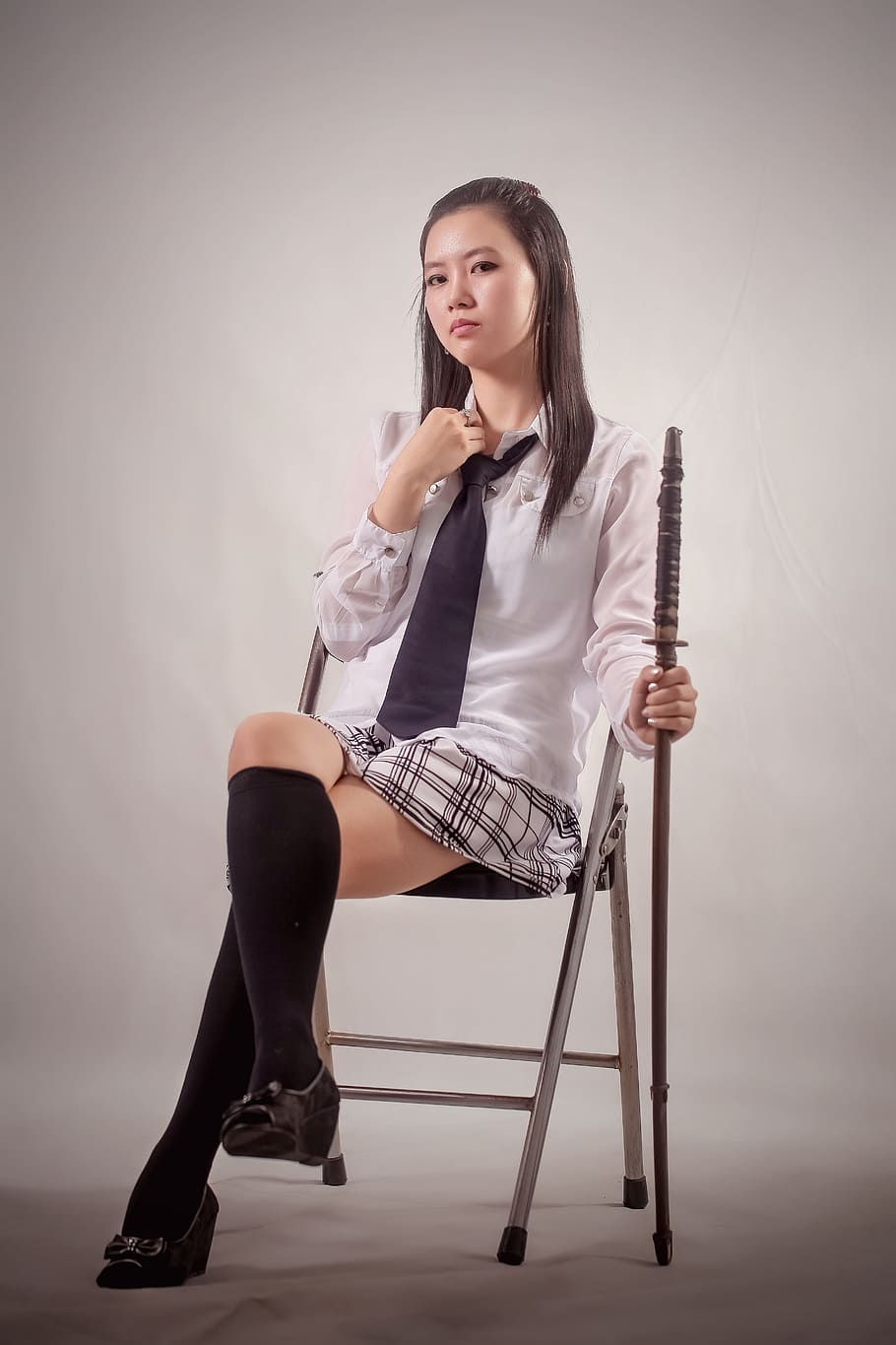 woman wearing white collared shirt, brown necktie, and white-and-black mini skirt while sitting and holding wooden sword HD wallpaper