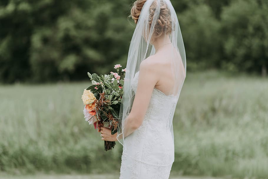 woman holding bouquet of flower, woman in white strapless wedding dress on green grass field holding flower bouquet, HD wallpaper