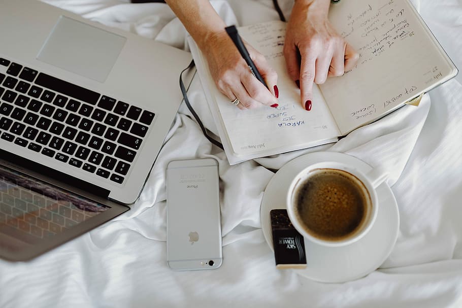 Woman working on a laptop while enjoying a breakfast coffee and chocolate in bed HD wallpaper