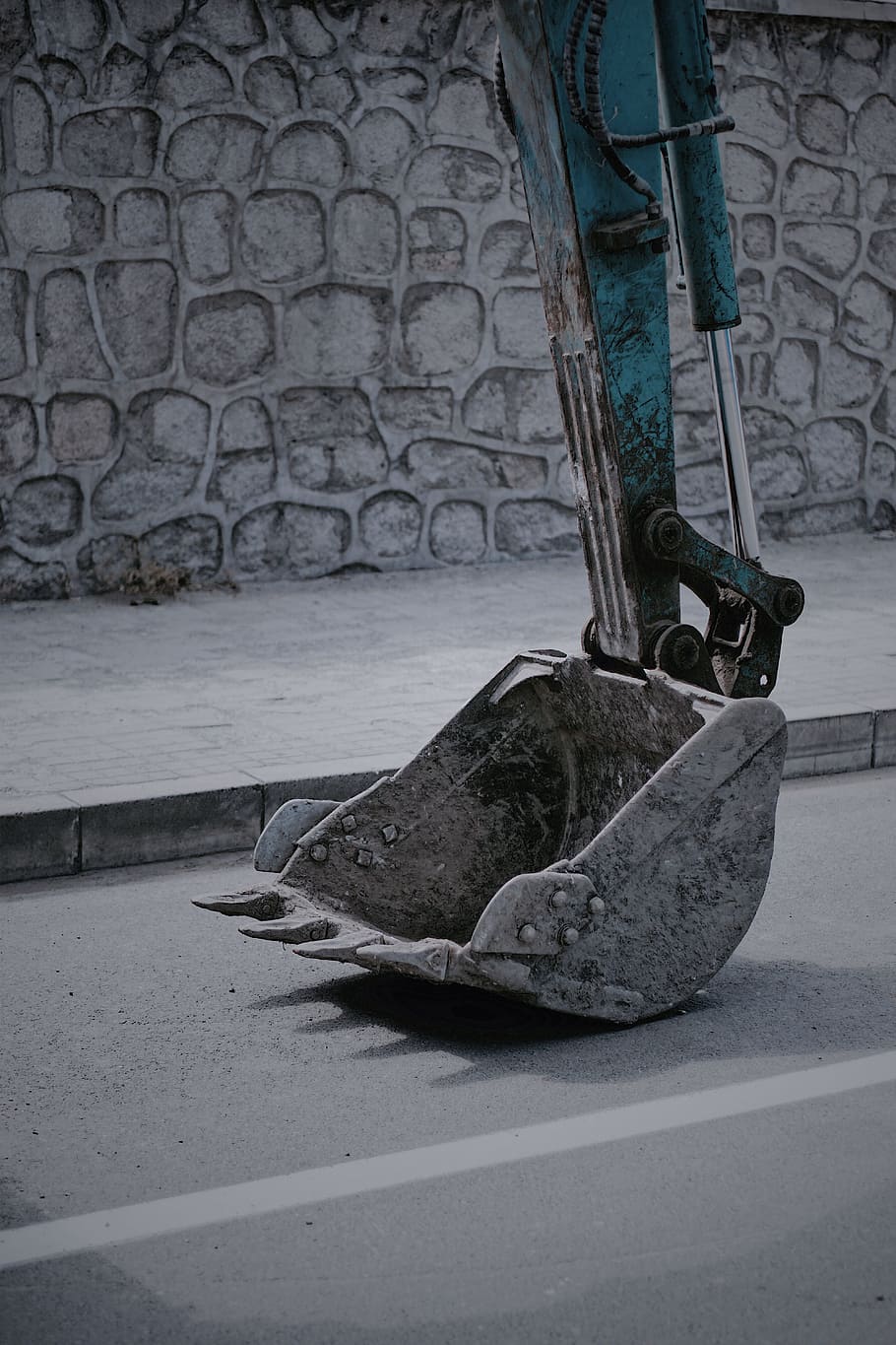 closeup photo of excavator bucket on road, grey and teal excavator bucket