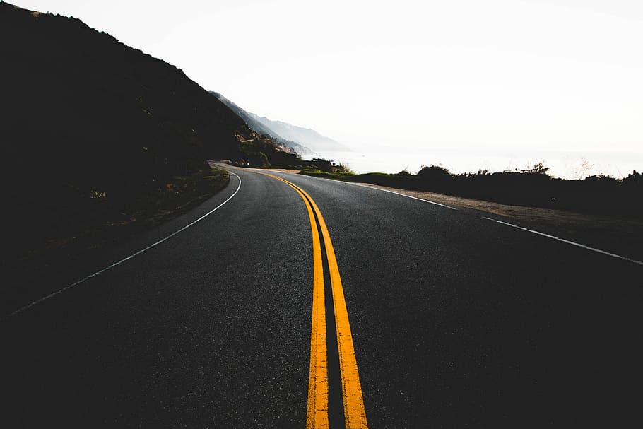 road between green bushes during daytime, yellow lines between concrete roads HD wallpaper