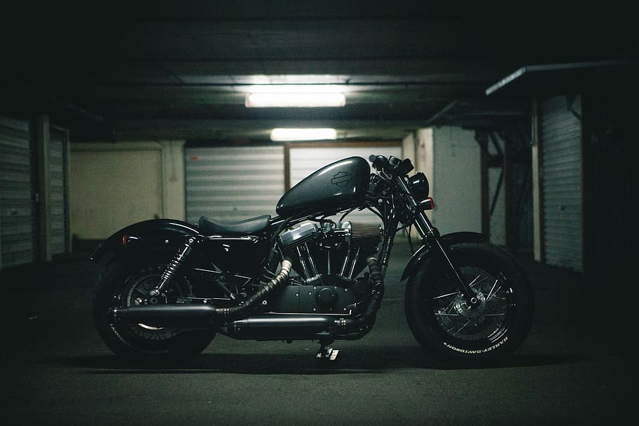 black bobber motorcycle inside garage, parked cruiser motorcycle on road